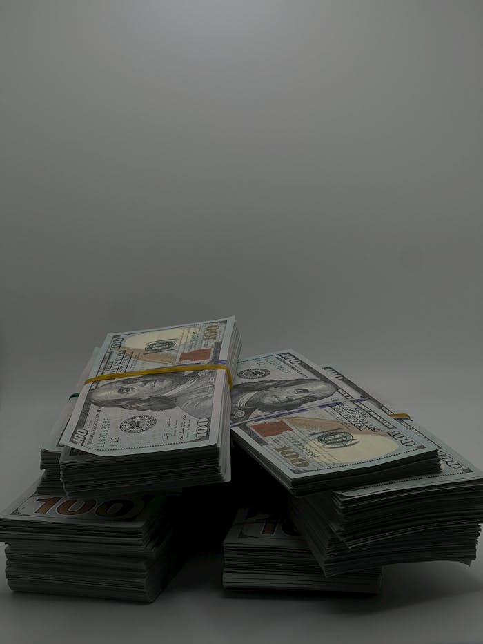 Piles of US hundred dollar bills stacked, representing wealth and finance.